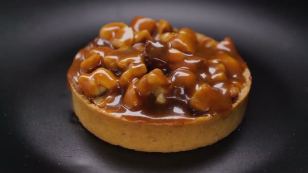 Tarta con nueces y caramelo girando sobre plato negro — Vídeos de Stock