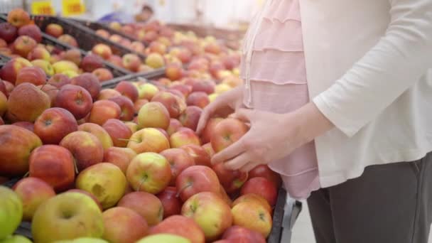 Zwangere vrouw kiezen van appels in supermarkt winkel — Stockvideo