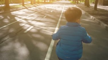 Asfalt yolda bisikletli küçük çocuk. Sevimli çocuk bisiklet parkurunda bisiklete binmeyi öğreniyor.