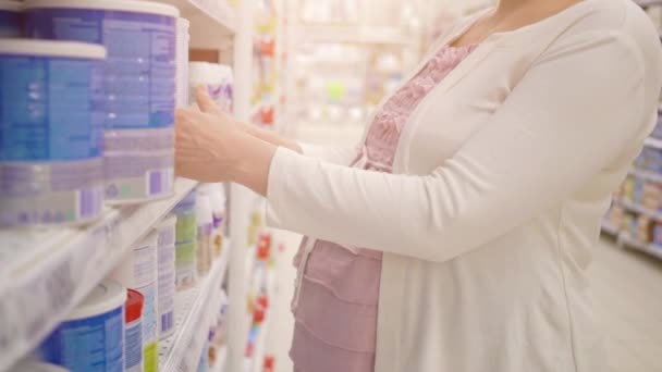 Беременная женщина выбирает сухое молоко в супермаркете — стоковое видео