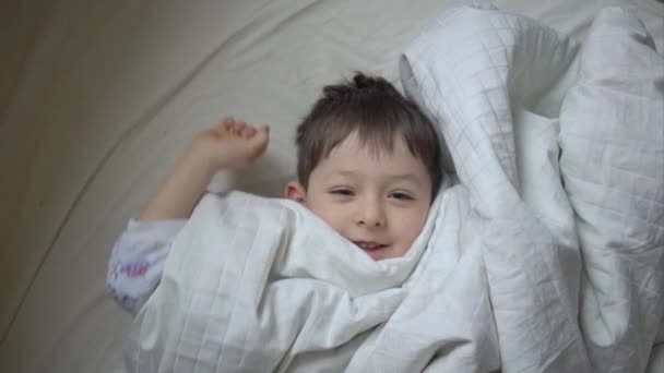 Top vy över söt liten pojke som sträcker sig i sängen hemma — Stockvideo
