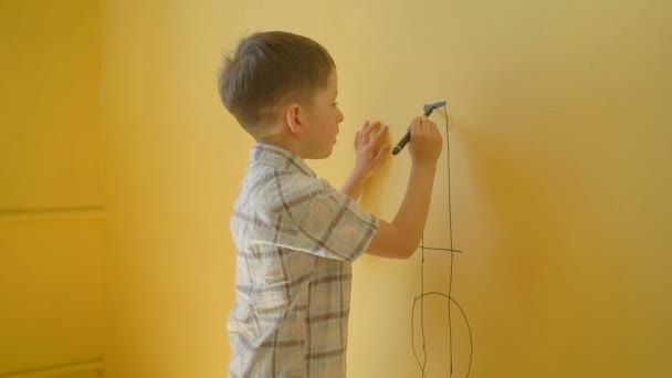 Kleine jongen tekenen op de gele muur thuis — Stockvideo