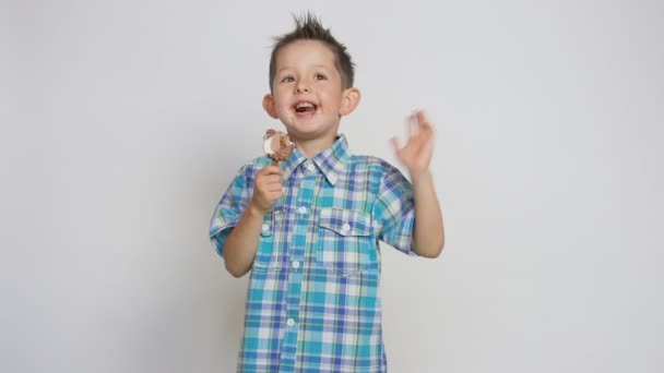 Lindo niño feliz, comiendo helado, sosteniendo un palo y sonriendo a la cámara — Vídeo de stock