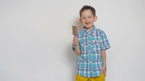 Niño emocionado con barra de helado de chocolate, cinco años de edad, sobre fondo blanco — Vídeos de Stock