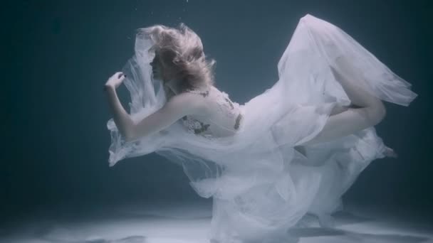 Bella donna che nuota sott'acqua in abito elegante bianco — Video Stock