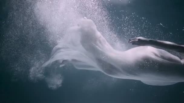 Красивая женщина плавает под водой в белом элегантном платье — стоковое видео