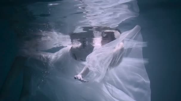 Gyönyörű nő úszunk víz alatti fehér elegáns ruhában — Stock videók