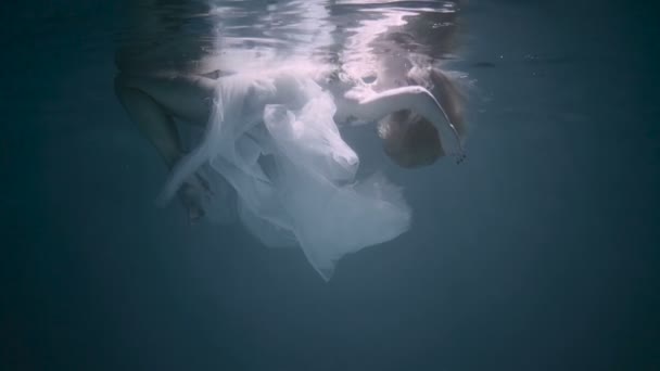 Mujer joven bajo el agua, ella está usando un vestido blanco . — Vídeos de Stock