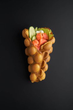 Hong kong or bubble waffle with fresh salmon and sauce on dark bakground. Street food concept clipart