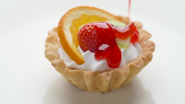 Tarta de postre de fruta con crema batida y cobertura de fresa sobre fondo blanco — Vídeos de Stock
