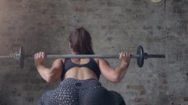 Siyah spor giyimli kadın halter egzersizi yapan bar tutuyor