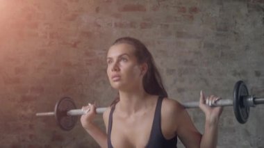 Siyah spor giyim fit güzel kız bir tuğla duvarın arka planda barbell ile çömelme yapıyor