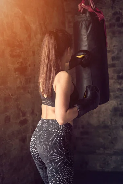 Rückansicht Mädchen in schwarzer Sportbekleidung beim Training mit Boxsack — Stockfoto