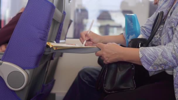 Жінка вирішує кросворд, сидячи в поїзді — стокове відео