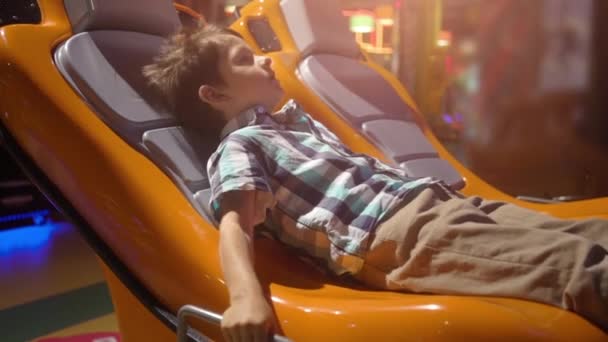 Zaskoczony małego chłopca w ruchomej fotelu interaktywnym — Wideo stockowe