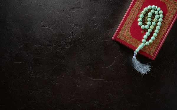 Corano e rosario perline su sfondo nero. Concetto islamico con spazio di copia, vista dall'alto — Foto Stock