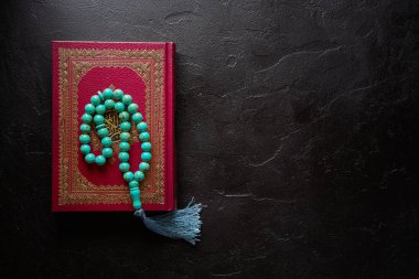 Siyah zemin üzerine Kur'an ve tespih boncukları. Kopya alanı ile İslami kavram, üst görünüm