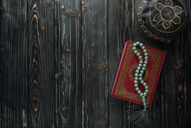 Tespih boncuk ve ahşap arka plan üzerinde dua şapka ile İslam kitap Kur'an. Kopyalama alanı ile İslami kavram