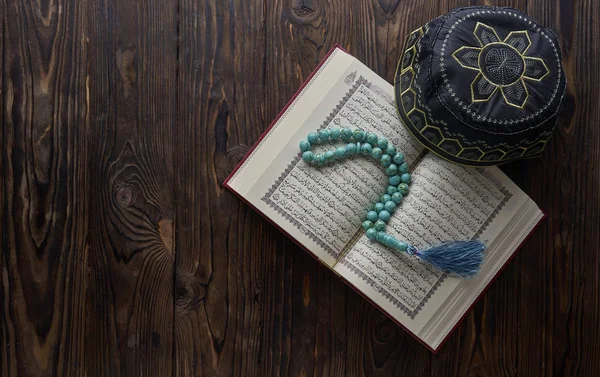Libro islámico Corán con cuentas de rosario y sombrero musulmán sobre fondo de madera. Concepto islámico con espacio de copia — Foto de Stock