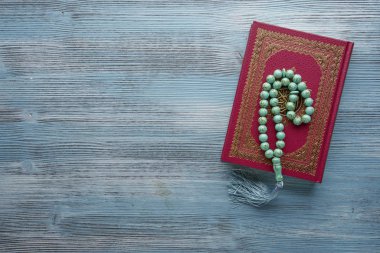 Ahşap arka plan üzerinde tespih boncuk ile İslam kitap Kuran. Kopyalama alanı ile İslami kavram