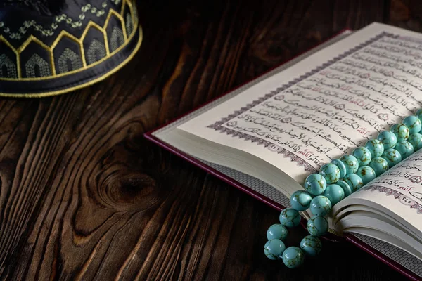 Libro aperto del Corano con rosario e cappello kopiah per musulmani sul tavolo di legno — Foto Stock