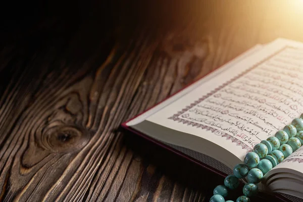 Ahşap masa üzerinde tespih boncuk ile İslami kitap Kuran