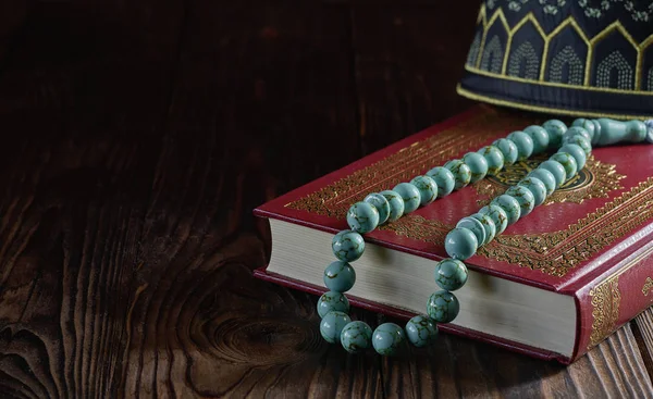 Libro islámico Corán con cuentas de rosario y sombrero kopiah para los musulmanes en la mesa de madera — Foto de Stock