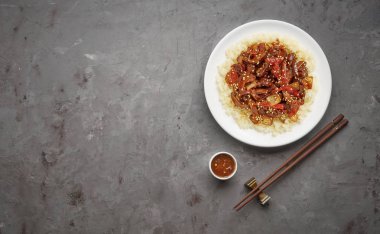 Gri taş arka planda sebze ve pirinç ile tatlı ve ekşi kızarmış domuz parçaları. Kopya alanı ile üst görünüm