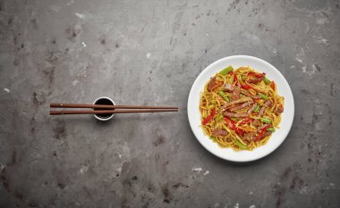 Gri taş arka planda sığır ve sebze ile Çin noodle. Üstteki görünüm, kopya alanı