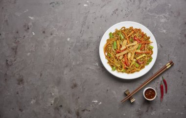 Gri taş arka planda sığır ve sebze ile Çin noodle. Üstteki görünüm, kopya alanı