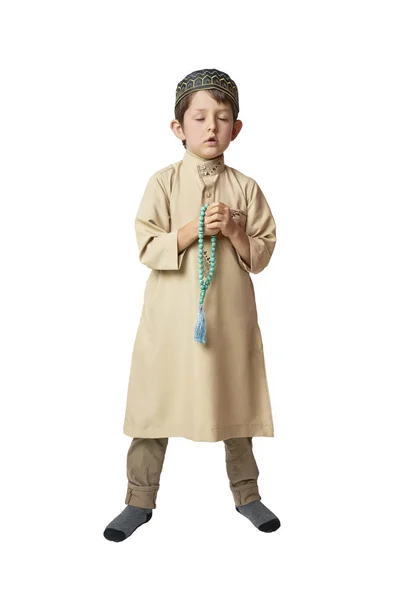 Piccolo ragazzo musulmano che prega e tiene perline di preghiera su sfondo bianco — Foto Stock