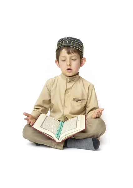 Niño rezando y sosteniendo el Corán con cuentas de rosario sobre fondo blanco — Foto de Stock