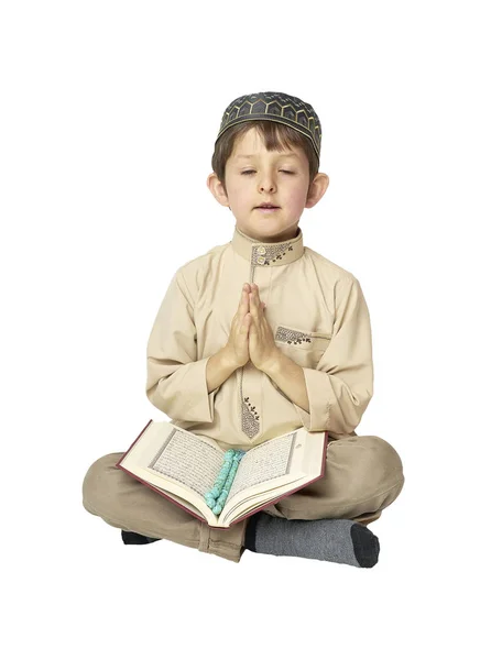 Niño rezando y sosteniendo el Corán con cuentas de rosario sobre fondo blanco — Foto de Stock