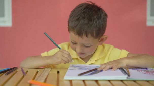 Söt liten pojke ritning i sitt album på träbord — Stockvideo