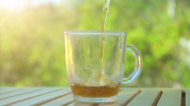 Çay parlak yaz güneş ışığı ile yeşil doğa arka plan üzerinde çaydanlık içine dökülen