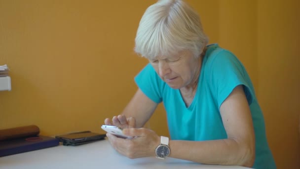 Mujer mayor usando smartphone en la sala de estar — Vídeos de Stock