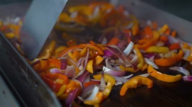 Şef bir restoranda açık ızgarada sebze kızartıp karıştırıyor.