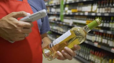 Marketteki şarap reyonunda kırmızı aport taraması yapan bir tezgahtar.