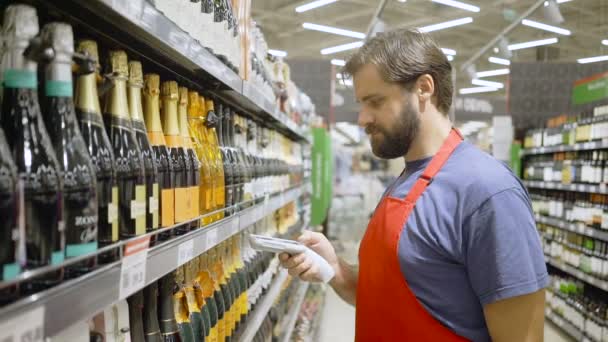 Empleado del supermercado en código de barras de escaneo de puerto rojo en la sección de vinos en el supermercado — Vídeos de Stock