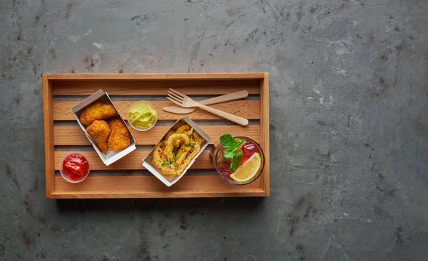 Τηγανητά πόδια κοτόπουλου με τραγανό χταπόδι και λεμονάδα σε ξύλινο δίσκο. Street food concept, οριζόντια σύνθεση σε πέτρινο φόντο — Φωτογραφία Αρχείου