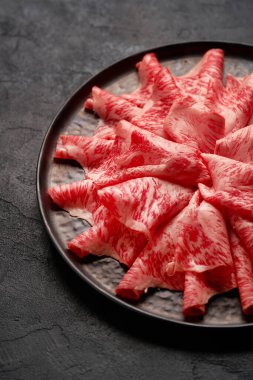 Japanese kobe beef sliced on ceramic plate on black background clipart