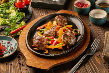 Tahta bir masada renkli dolmalık biberli biftek.