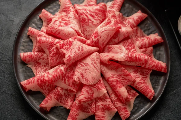 Shabu Shab için hazırlanmış seramik tabakta dilimlenmiş Japon wagyu bifteğinin detaylı bir görüntüsü.