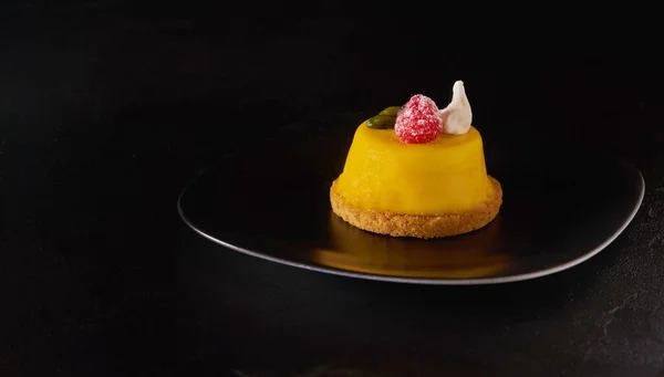 Mousse ciasto mango deser pokryte żółtą glazurą na czarnej płycie — Zdjęcie stockowe
