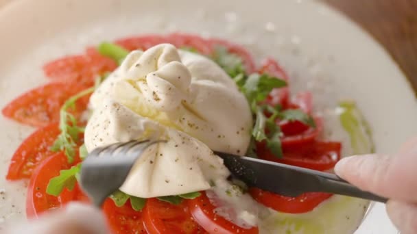Essen köstlichen Burrata-Käse mit Tomaten schneiden mit Messer und Gabel — Stockvideo