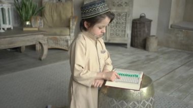 Duacı şapkalı ve Arapça elbiseli sevimli bir çocuk kutsal Kur 'an kitabı okuyarak Allah' a dua ediyor, Hz. Muhammed 'in doğu iç kesimlerinde kutsal ruh sembolü kavramı.