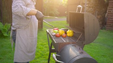 Mangal tabağında ızgara yapan genç bir adam. Parlayan kömürlerle, yaz pikniği zamanı. Bahçesinde ateş olan barbekü ızgarası.