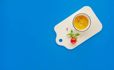 Beyaz seramik panoda baharatlı organik zeytinyağı. Mavi arka plan, fotokopi alanı, sağlıklı gıda konsepti.