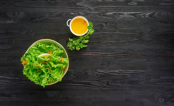 Čerstvý zelený zeleninový salát se salátem a mrkví v misce na tmavém dřevěném pozadí, zdravá vegetariánská výživa a dietní koncept, horní pohled s kopírovacím prostorem — Stock fotografie