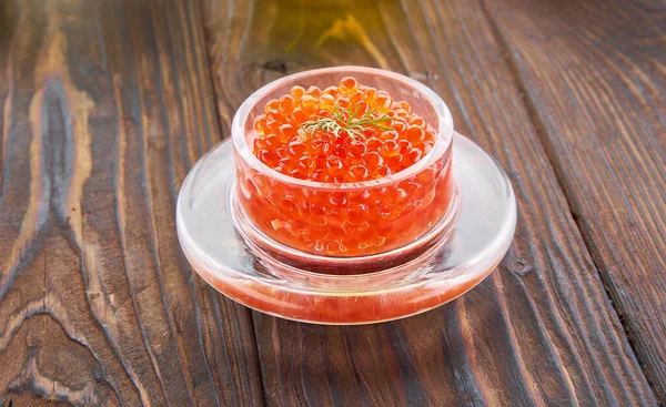 Caviar rojo en el frasco de vidrio sobre el fondo de madera — Foto de Stock
